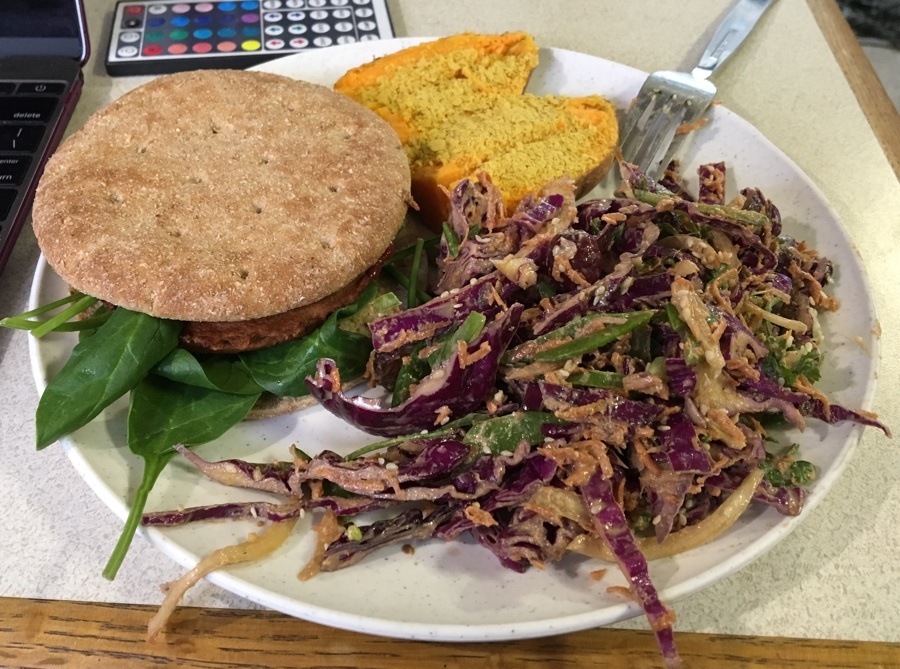 Veggie burger with half a sweet potato with nutritional yeast and sesame purple cabbage and carrot slaw.