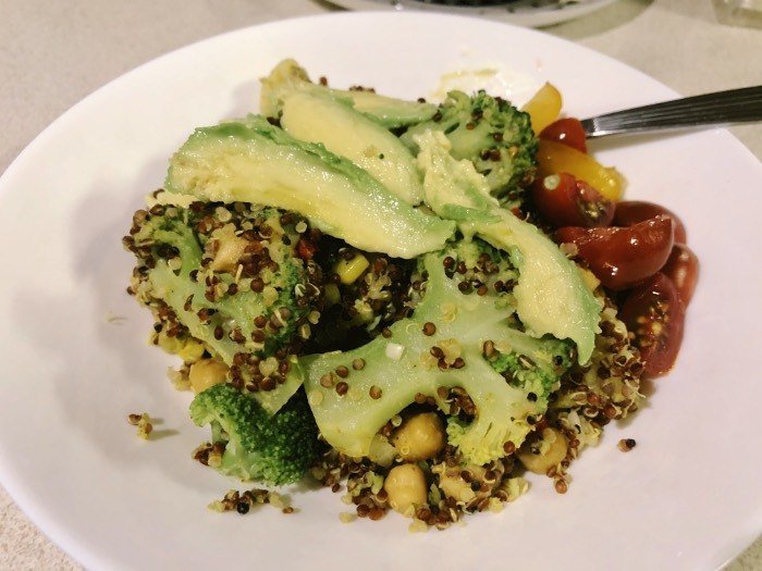 chickpea quinoa curry bowl served with avocado and cherry tomatoes.