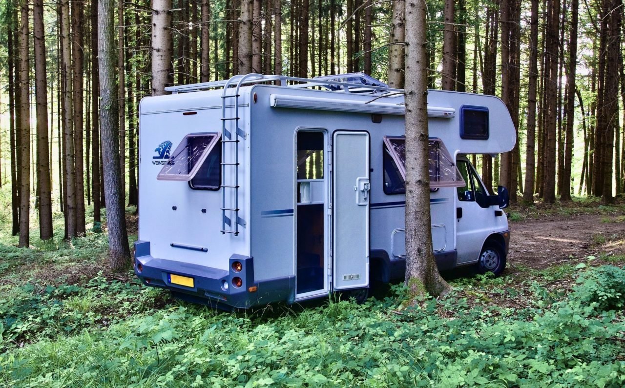 class c motorhome in the trees with doors and windows open.