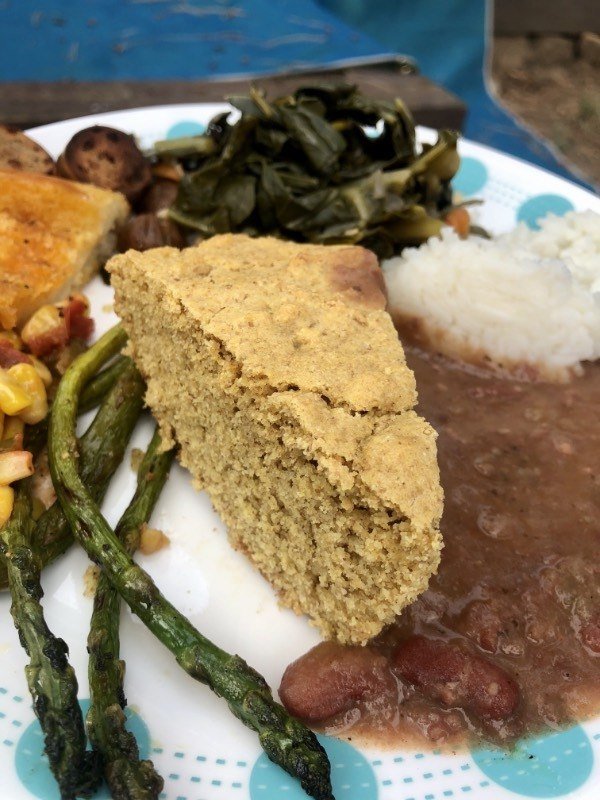 a slice of vegan skillet cornbread on a plate with other food.