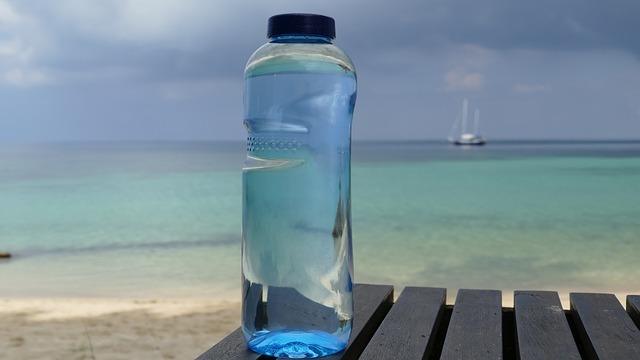 water bottle on the beach with the sea and a boat in the background.