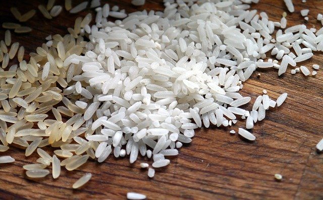 brown and white rice grains on a wooden surface.