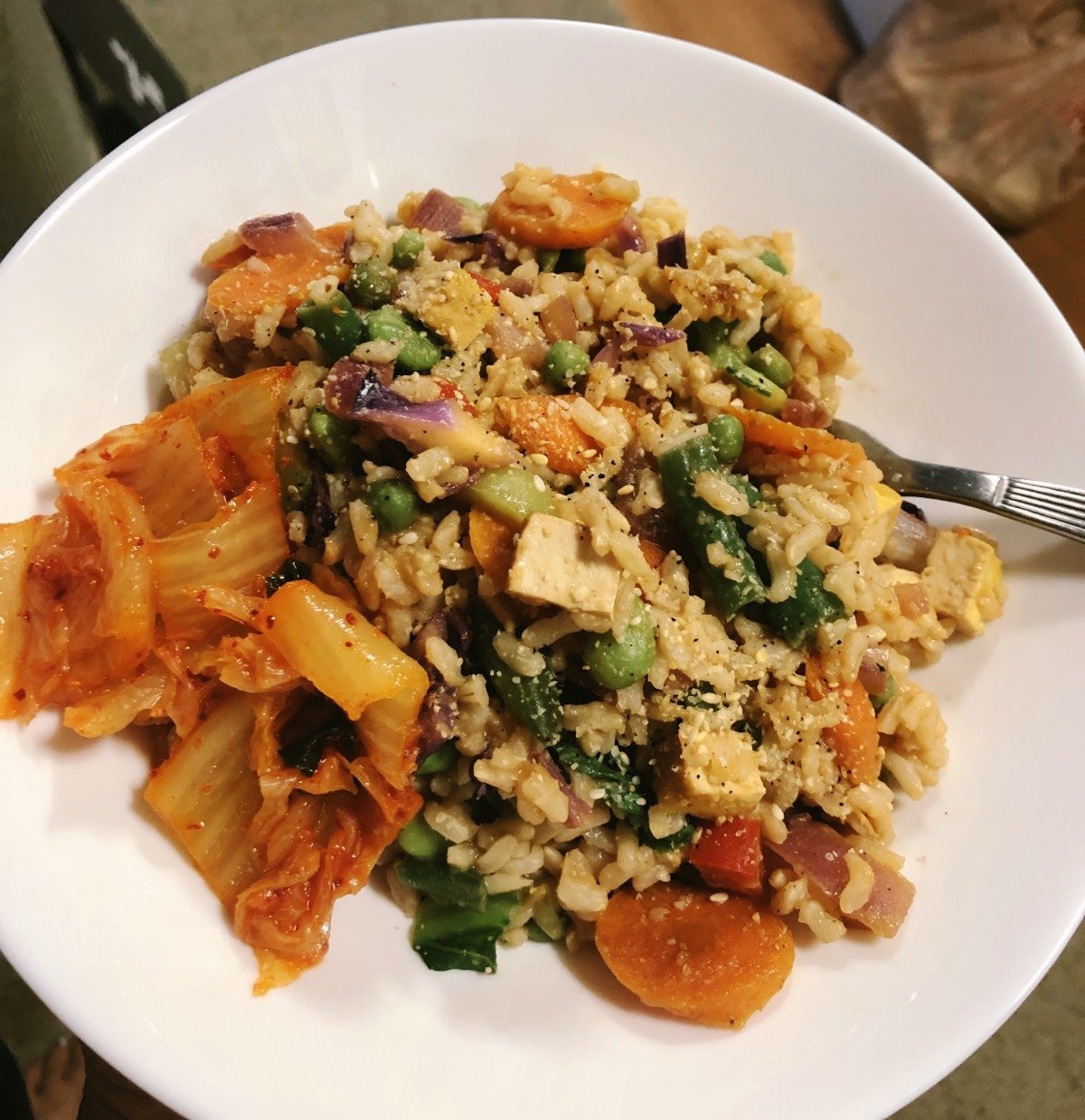 tofu fried rice in a white bowl with added kimchi.