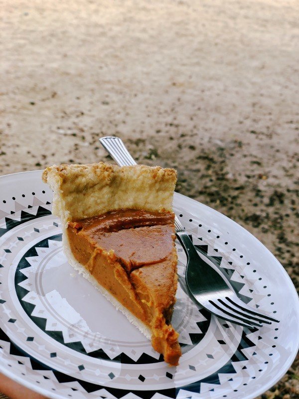slice of vegan pumpkin pie on a black and white plate.