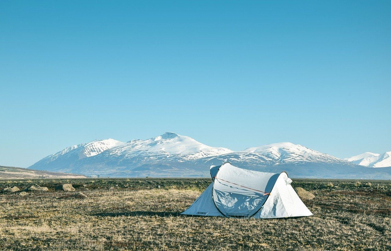 a tent set up to camp with mountains in the background.