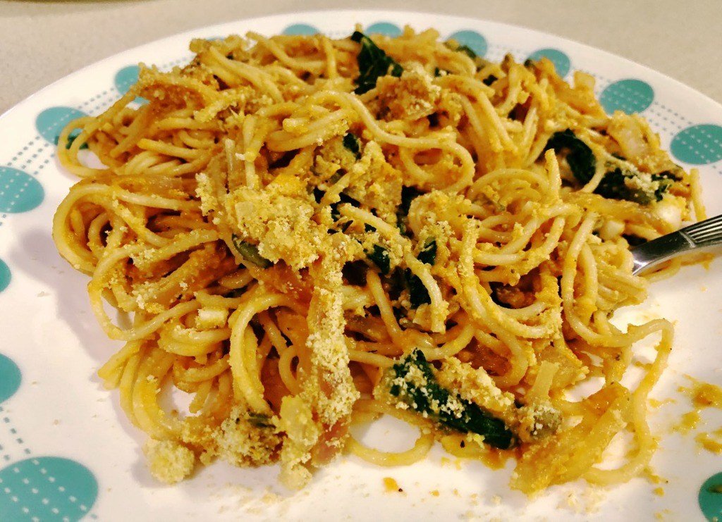 pumpkin sage pasta with kale and vegan parmesan on a plate.