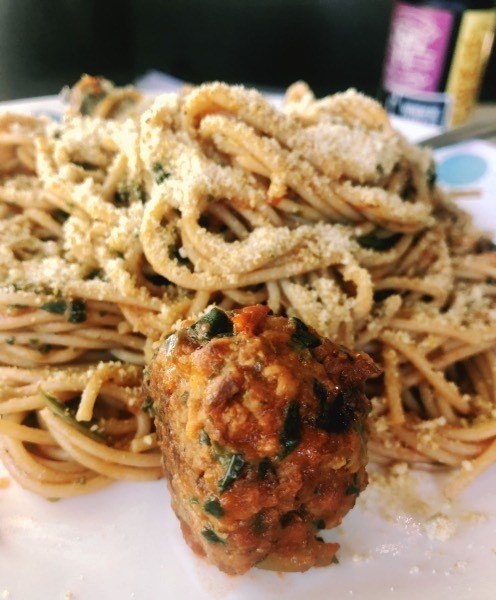 spaghetti in a red sauce and a vegan meatball on a plate.