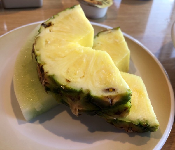 melon and pineapple slices on a small white plate.