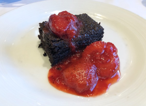 vegan chocolate cake and strawberries on a white plate.