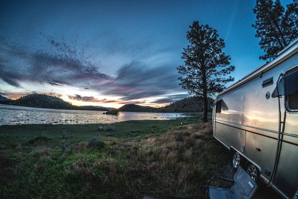 airstream rv parked on a lake.