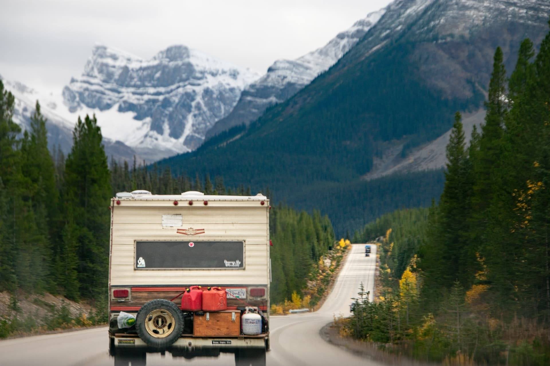 rv driving towards snow topped mountains.