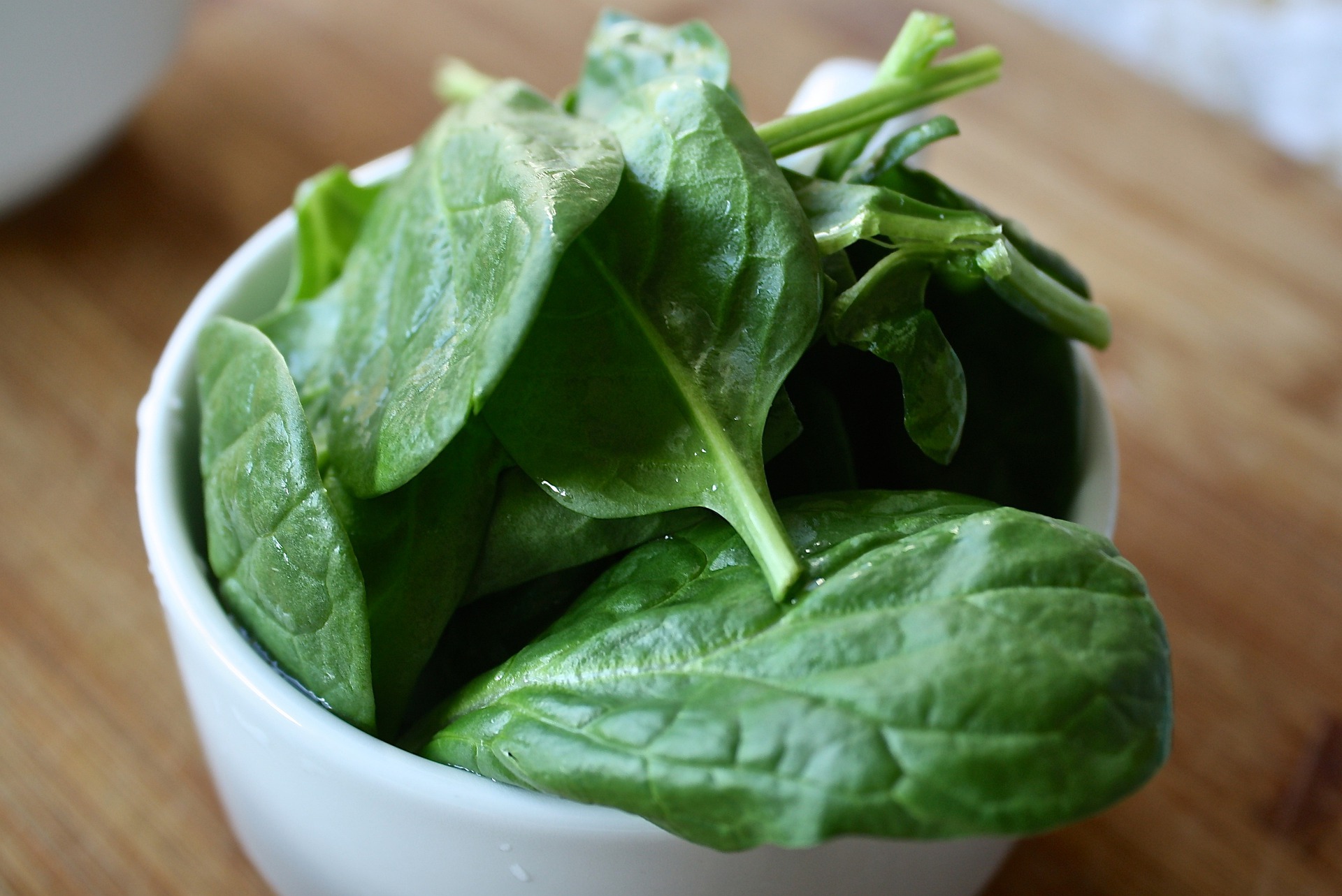 fresh spinach leaves in a white bowl.