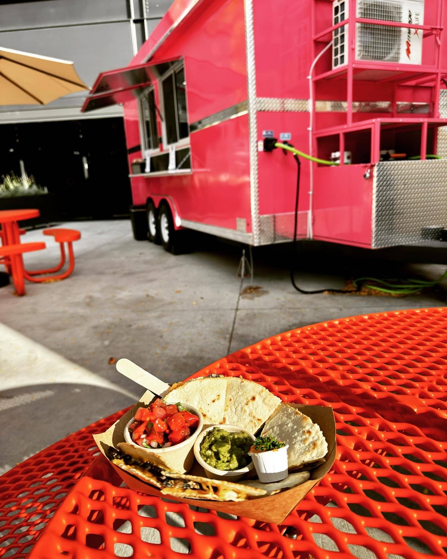 luv tempeh quesadilla on a red table with the bunny chow trailer in the background.