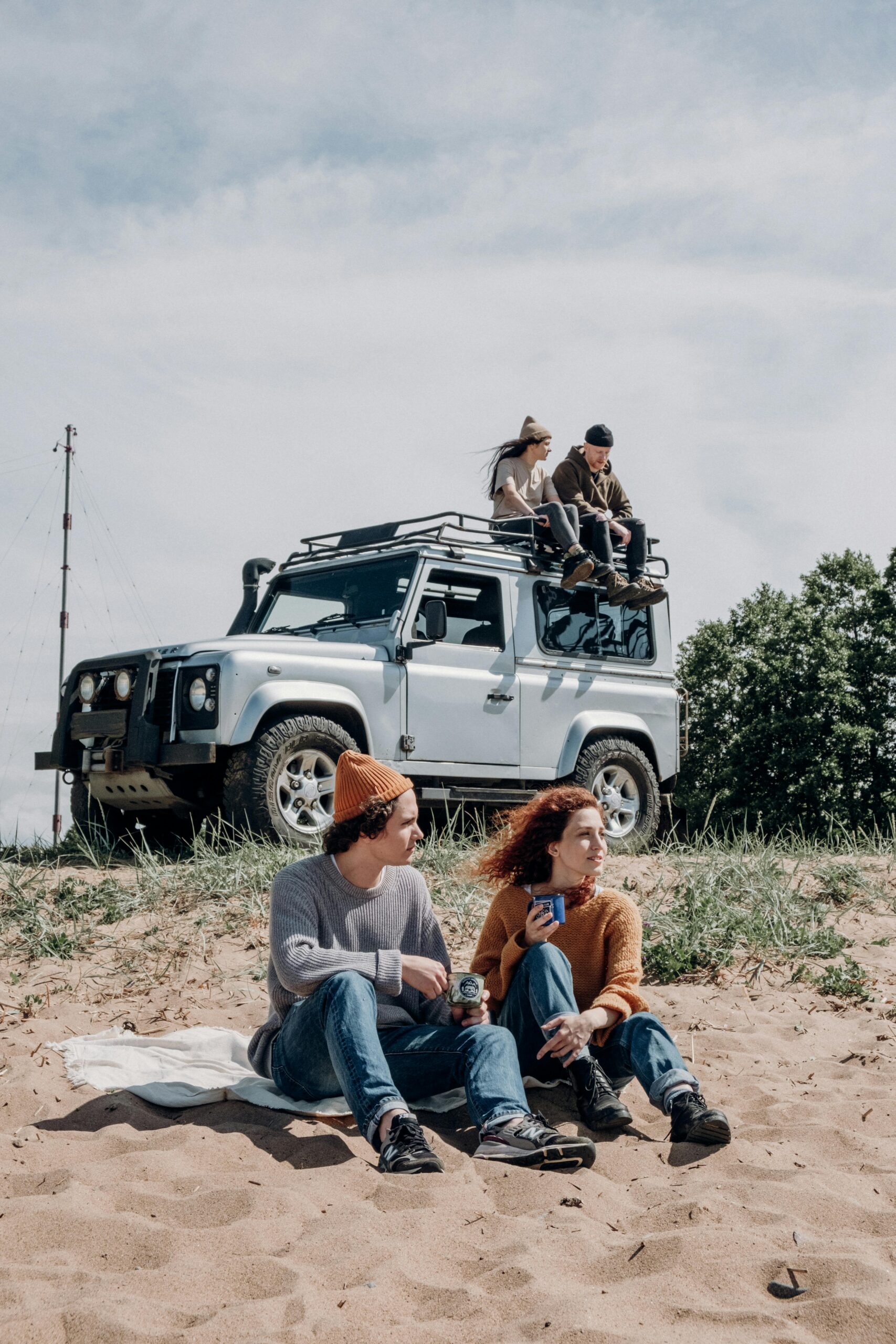 two people sitting on the ground with a 4wd vehicle in the background.